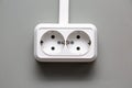 White European dual power socket for two entrances on a light gray wall. Horizontal orientation. Isolated.