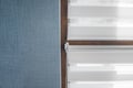 White fabric roller blinds on the plastic window with wood texture in the living room with blue wall. Royalty Free Stock Photo