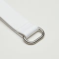 White fabric strap featuring a shiny metal D-ring buckle. The strap has a textured weav Royalty Free Stock Photo