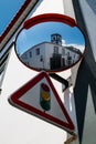 Traffc sign and a traffic mirror, corner of a house