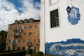 White facade with portugal azulejo in front of beige residential house with drying cloths