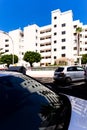 White facades of houses are reflected on car windows