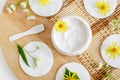 White facial mask face cream, hair mask, body butter, facial cleanser in the small white jar, cotton pads and wild flowers.