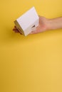 White family paper house in man hand on yellow background paper. Minimalistic style. Copy space. View from above. Horizontal Royalty Free Stock Photo