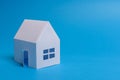 White family paper house over block of flats on blue background paper. Minimalistic and simple concept, style. Copy space. Royalty Free Stock Photo