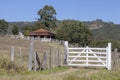 White farm gate, with hills and house Royalty Free Stock Photo