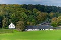 White farm with timberwork in the beautiful summer field landscape with yellow flowers meadow landscape, green trees