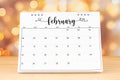 White February 2024 desk calendar on wooden table with gold light bokeh background Royalty Free Stock Photo