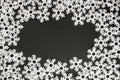 White felt snowflakes massed in a frame pattern on a black background