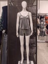 White female abstract mannequin in gray pajamas on a pedestal in a store