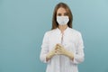 White female doctor in a mask and coat on a blue background