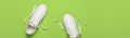 White female fashion sneakers on green background. Flat lay top view copy space. Women`s shoes. Stylish white sneakers. Fashion