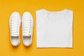 White female fashion sneakers, white T-shirt on yellow orange background. Flat lay top view copy space. Women`s shoes