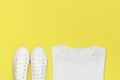 White female fashion sneakers, white T-shirt on yellow orange background. Flat lay top view copy space. Women`s shoes. Stylish Royalty Free Stock Photo