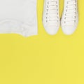 White female fashion sneakers, white T-shirt on yellow orange background. Flat lay top view copy space. Women`s shoes. Stylish Royalty Free Stock Photo