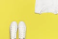 White female fashion sneakers, white T-shirt on yellow orange background. Flat lay top view copy space. Women`s shoes. Stylish Royalty Free Stock Photo