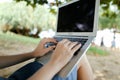 White female hands using laptop with sand in background, black screen. Royalty Free Stock Photo