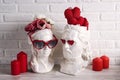 White female and male plaster heads with heart shaped glasses, hearts, flowers and candles against the white brick wall Royalty Free Stock Photo