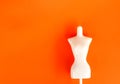 White female mannequin figure on bright orange background