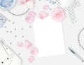 White feminine background. Flat lay. Pink roses, mirror, leaves, gift, bag.