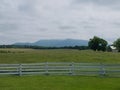 White fence, green grass, and mountains in the distance Royalty Free Stock Photo