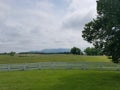 White fence, green grass, and mountains in the distance Royalty Free Stock Photo