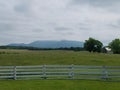 White fence, green grass, and mountains in the distance Royalty Free Stock Photo