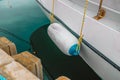 White fenders suspended between a boat and dockside for protection. Maritime fenders Royalty Free Stock Photo