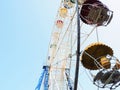 White Ferris wheel with multi-colored cabins against the blue sky. Soviet era amusement ride