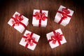 Five white festive gift boxes with red bows on a wooden table Royalty Free Stock Photo