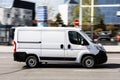 White Fiat Ducato cargo van is driving fast on the street, side view. Light commercial vehicle in motion