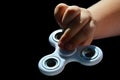 White fidget spinner toy held in left hand of small girl, black background Royalty Free Stock Photo