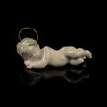 White figurine of baby Jesus on a black background with reflection. Royalty Free Stock Photo