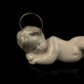 White figurine of baby Jesus on a black background with reflection. Royalty Free Stock Photo