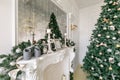 White fireplace decorated with candles and fir branches. Decorated Christmas tree. Classic apartments, morning in hotel Royalty Free Stock Photo