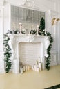 White fireplace decorated with candles and fir branches. Decorated Christmas tree. Classic apartments, morning in hotel Royalty Free Stock Photo