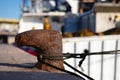 A rusty bollard on the quay. A white fishing trawler is moored there. Royalty Free Stock Photo