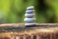 White stones cairn, poise light pebbles on wooden stump in front of green natural background, zen like, harmony and balance Royalty Free Stock Photo