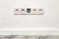 White five-way wall power socket on white wall