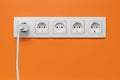 White five-way wall power socket on white wall