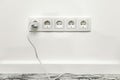 White five-way wall power socket on white wall