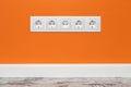 White five-way wall power socket on orange wall