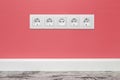 White five-way wall power socket on pink wall
