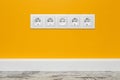 White five-way wall power socket on yellow wall