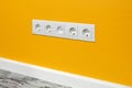 White five-way wall power socket on the yellow wall