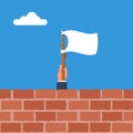 White flag holding in hand behind a brick wall. Flag surrender.