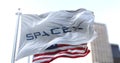 White flag with the SpaceX logo flapping in the wind with the American stars and stripes flag in the background