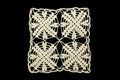 White crocheted coaster lace doily on black background.