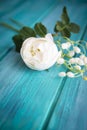White flower on teal blue wooden background. A bouquet of white roses and lillies of the valley