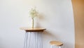 White flower in vase on table and wooden stool chair with concrete wall and orange pastel wall Royalty Free Stock Photo